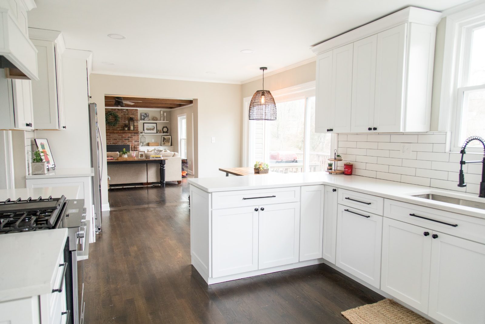 White kitchen with peninsula, subway tile and dark wood floors