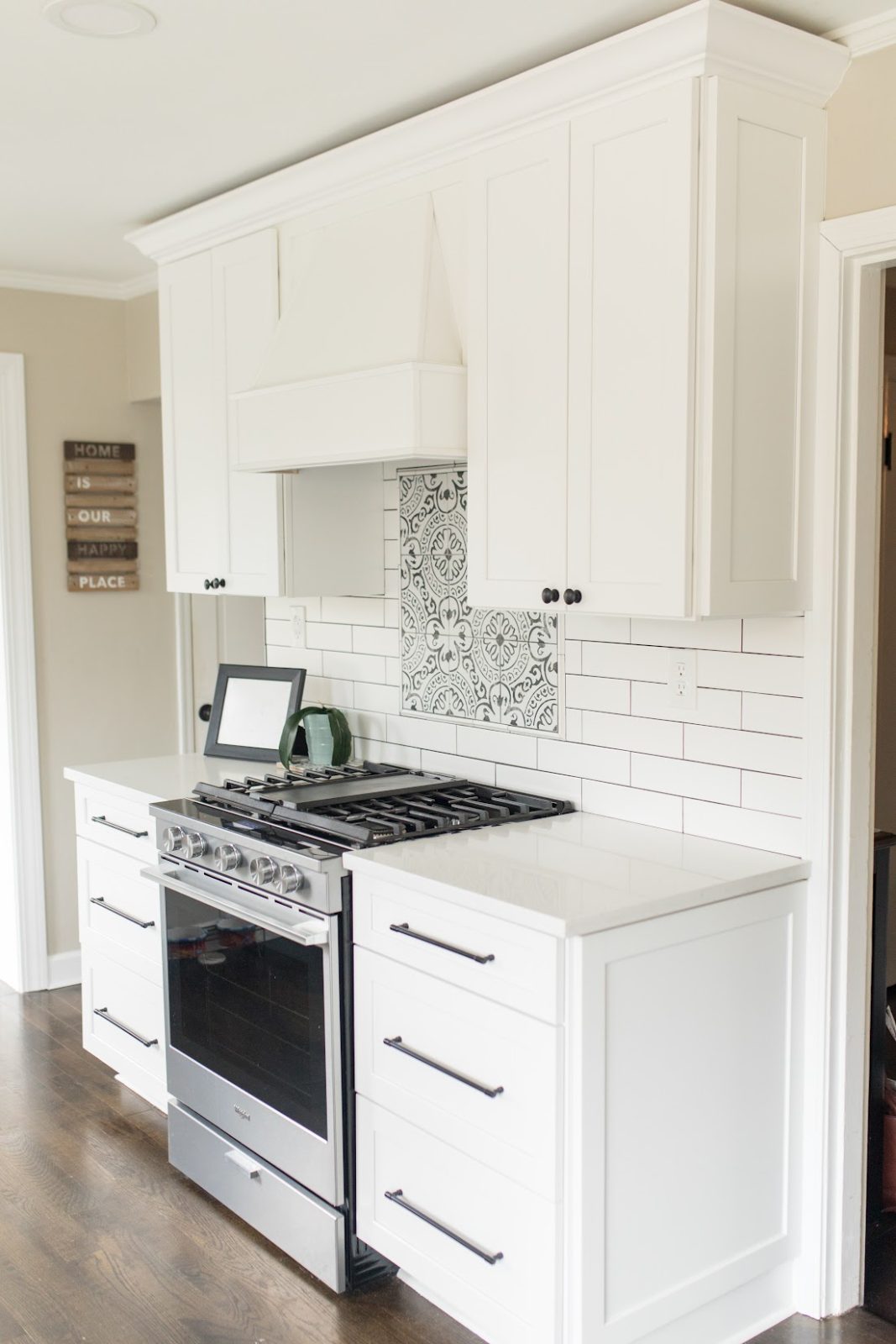 White shaker cabinets and a stainless gas range with tile backsplash